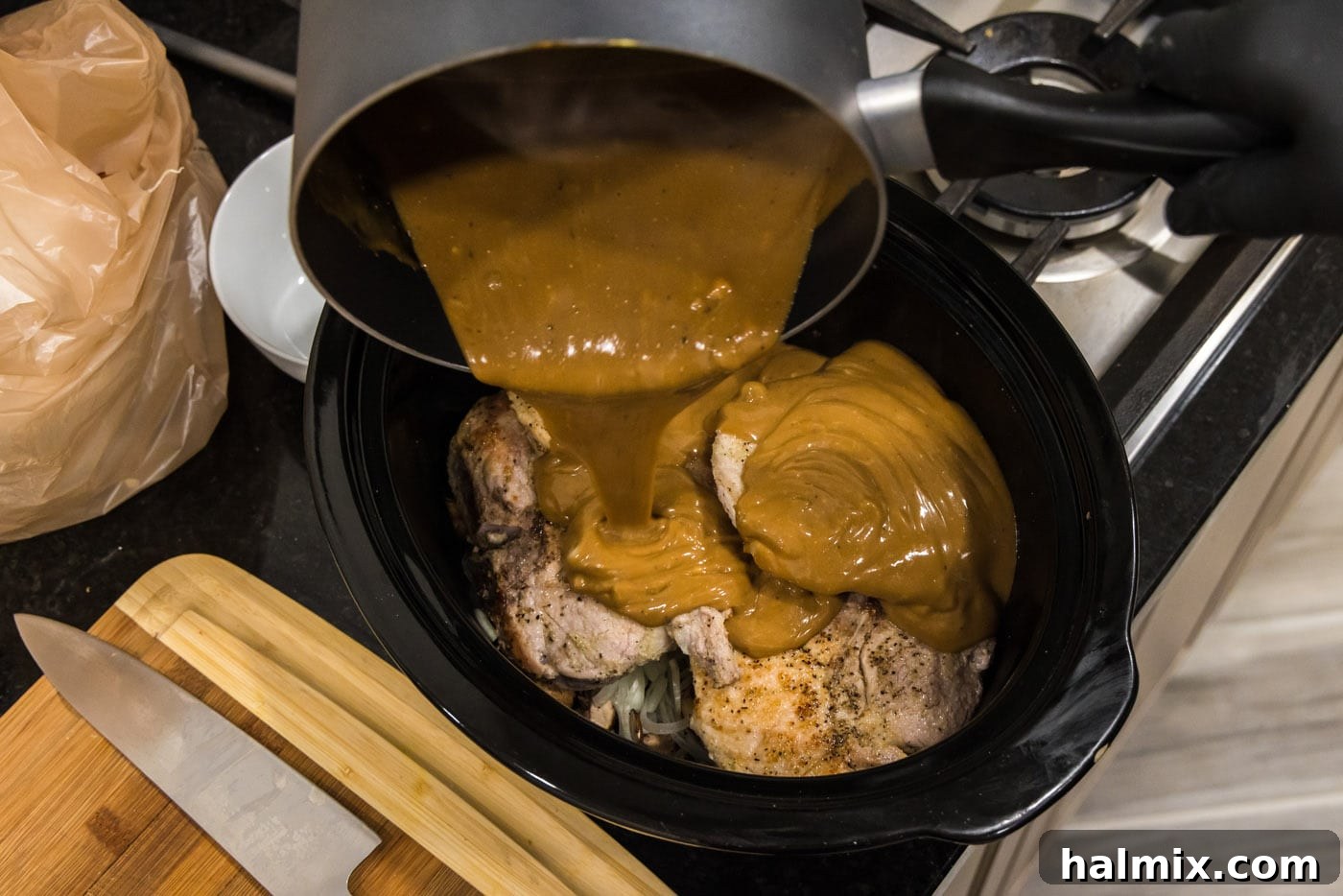 pouring brown gravy over pork chops in crockpot