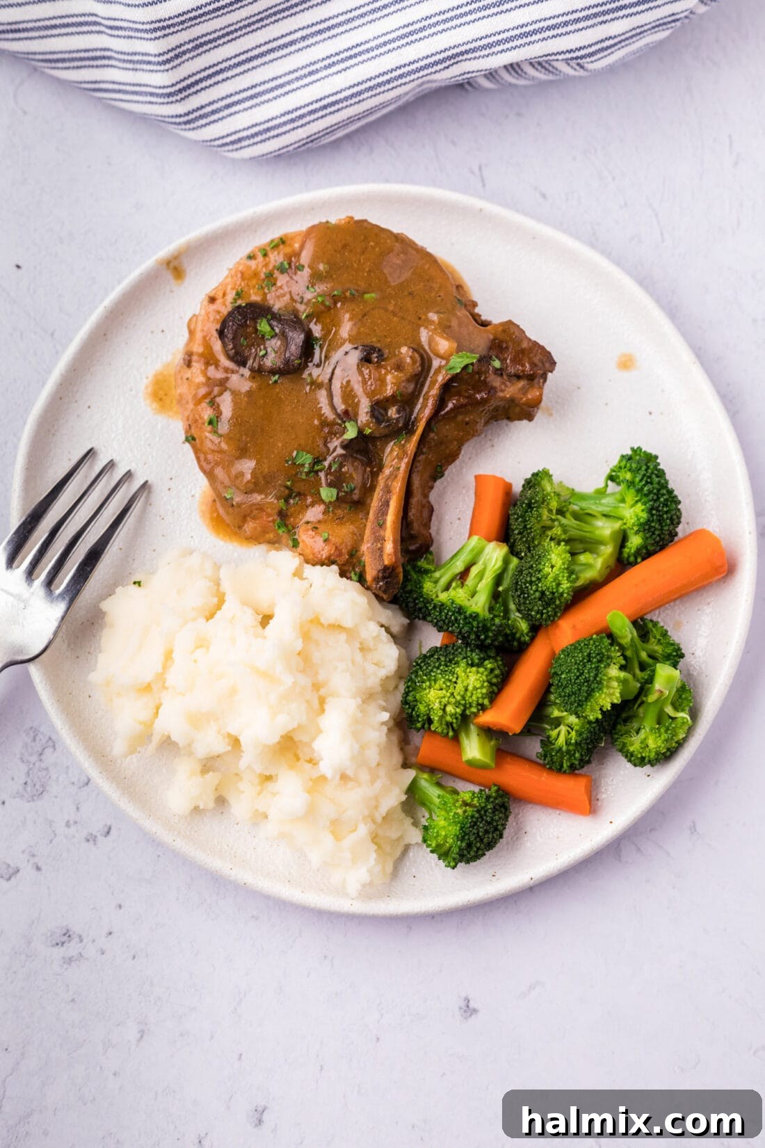 Crockpot Pork Chop served on a plate with mashed potatoes and mixed vegetables