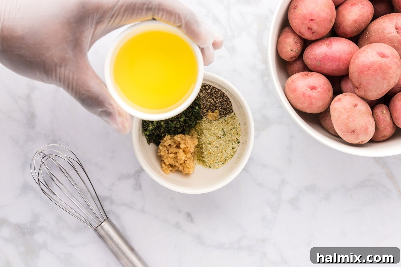 olive oil being poured over a bowl of seasonings