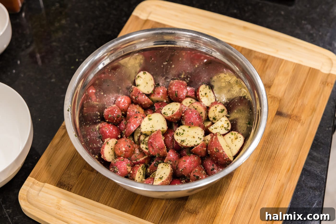 baby red potatoes tossed with olive oil and seasoning in a large bowl