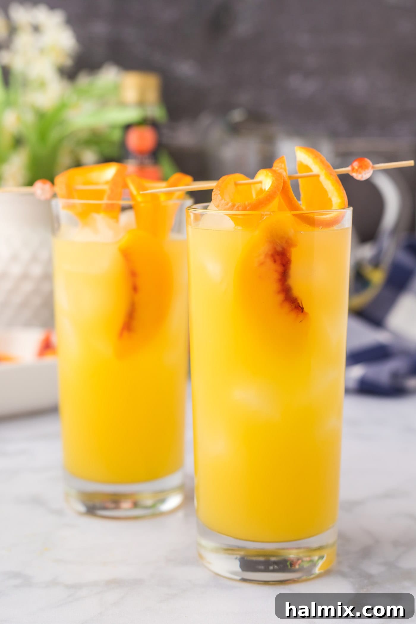 Velvet Peach Sunset 10 Fuzzy Navel cocktail with skewered orange slices and peach slices