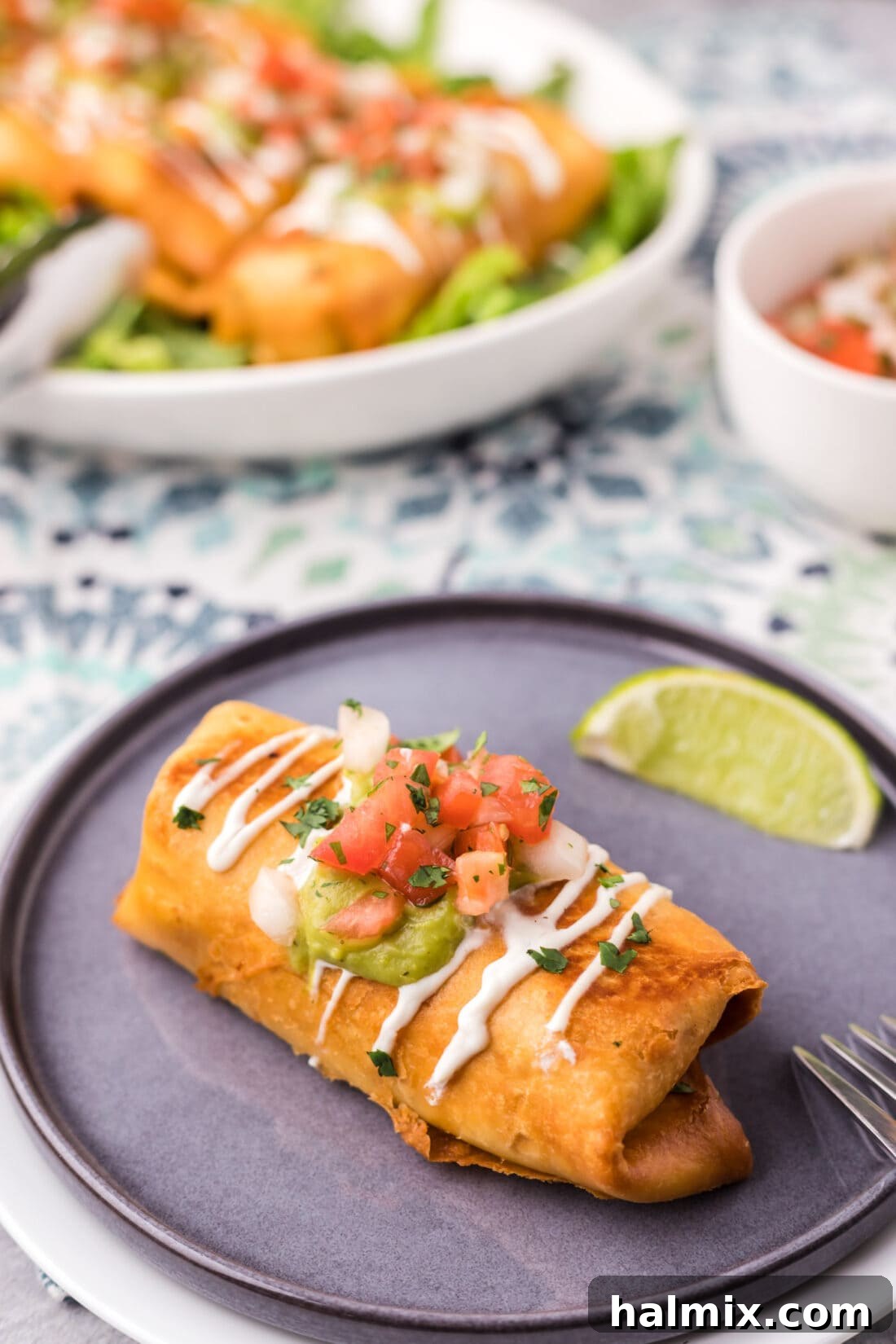 Deep-Fried Mexican Delights 3 A single chicken chimichanga on a white plate, accompanied by a fresh lime wedge, highlighting its golden crisp texture