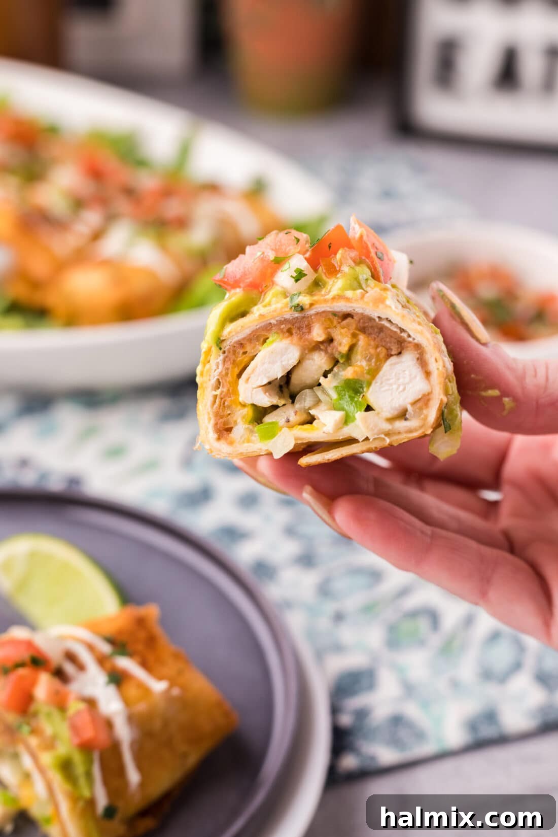 Deep-Fried Mexican Delights 21 Hand holding half of a Chimichanga, showing the delicious filling inside with melted cheese and chicken