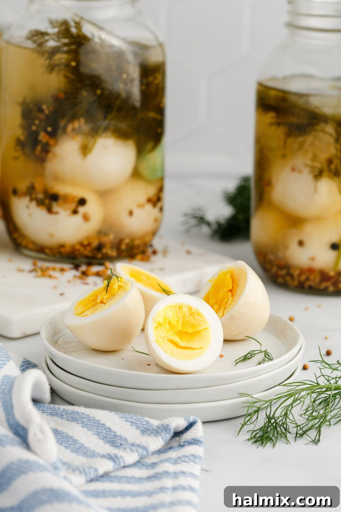 Two Pickled Eggs cut in half on a plate with jars of Pickled Eggs in the background