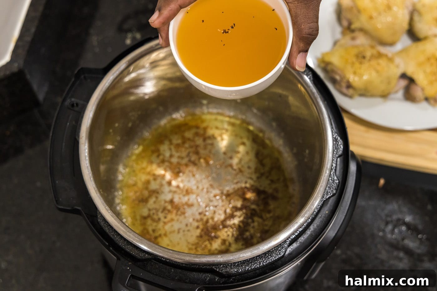 Adding chicken stock to deglaze the Instant Pot, scraping up delicious brown bits.