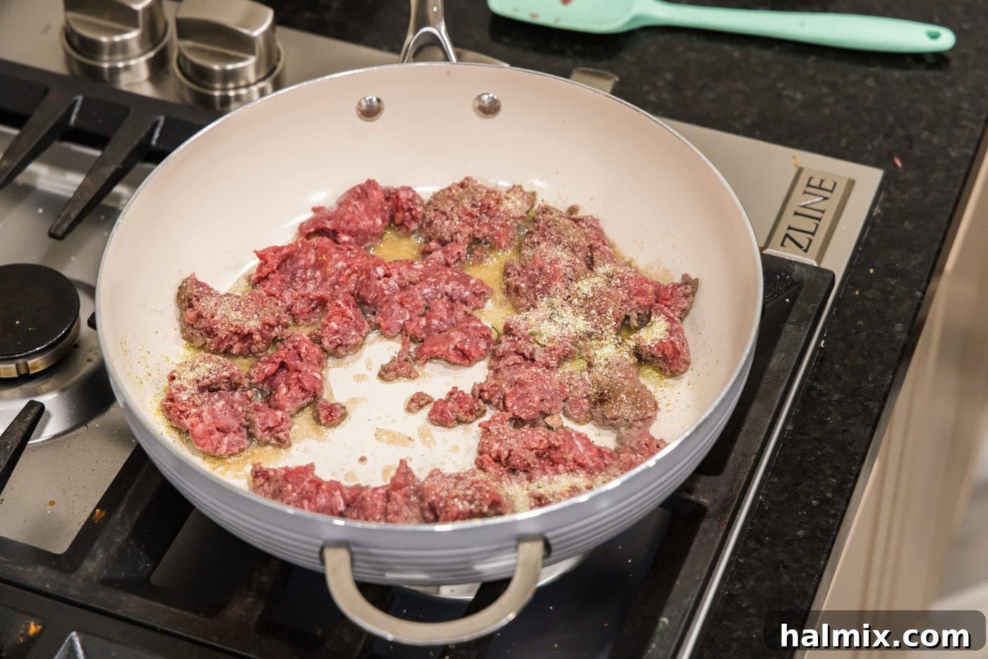 Browning ground beef in a skillet with olive oil, ready for taco seasoning and onions.