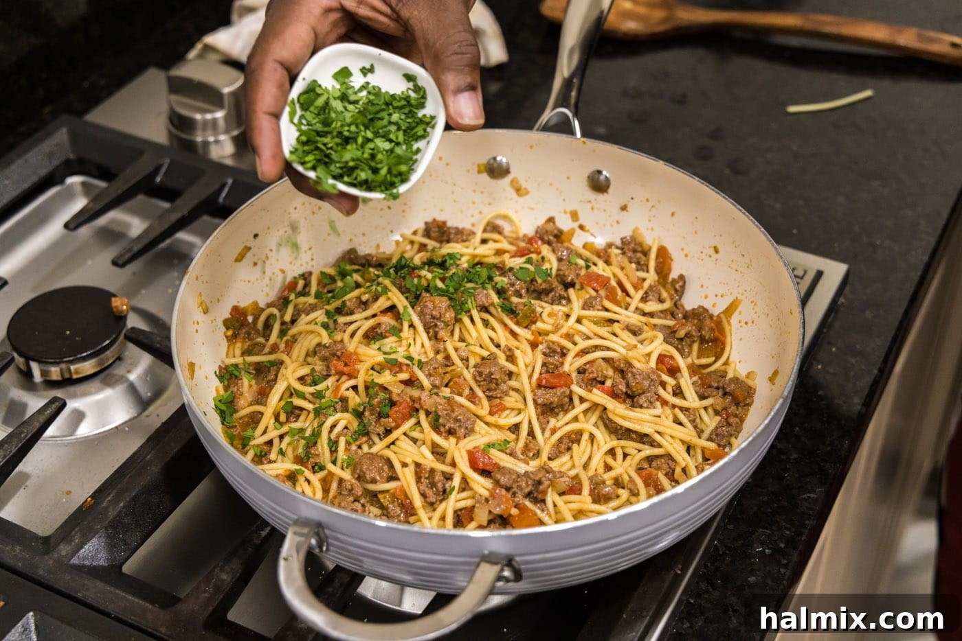 Adding fresh chopped cilantro to the finished taco spaghetti in the skillet, for a final burst of freshness.