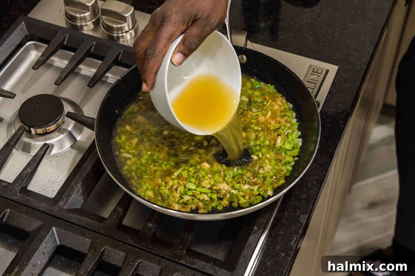 Spicy Southern Comfort Rice 7 Pouring rich chicken stock into the skillet with sautéed celery, green pepper, and onion, creating the flavorful base for the rice.