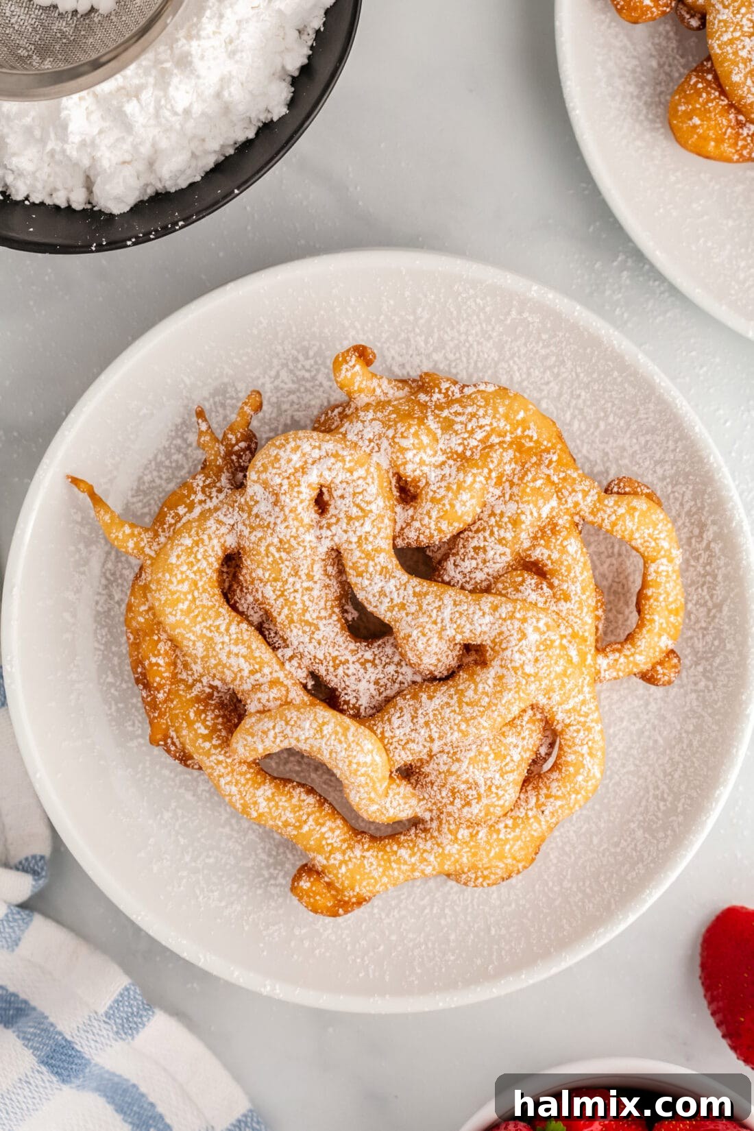 Golden Carnival Whirl 3 Overhead photo of a Funnel Cake topped generously with powdered sugar, ready to be enjoyed