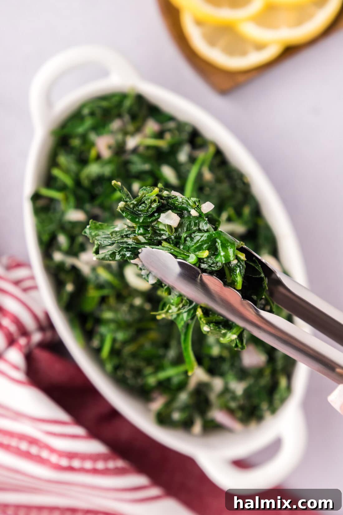 Perfectly Sautéed Spinach held by a pair of tongs, ready to be served.