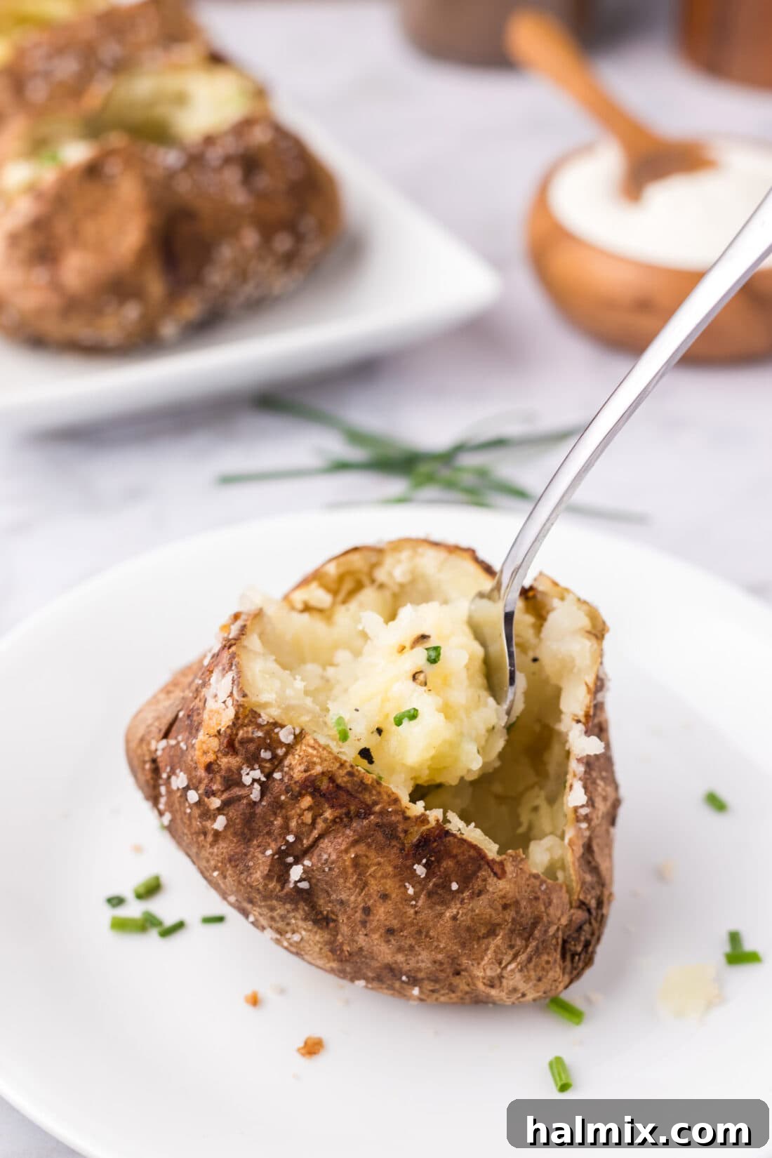 Baked Potato split open on a plate with a fork in it