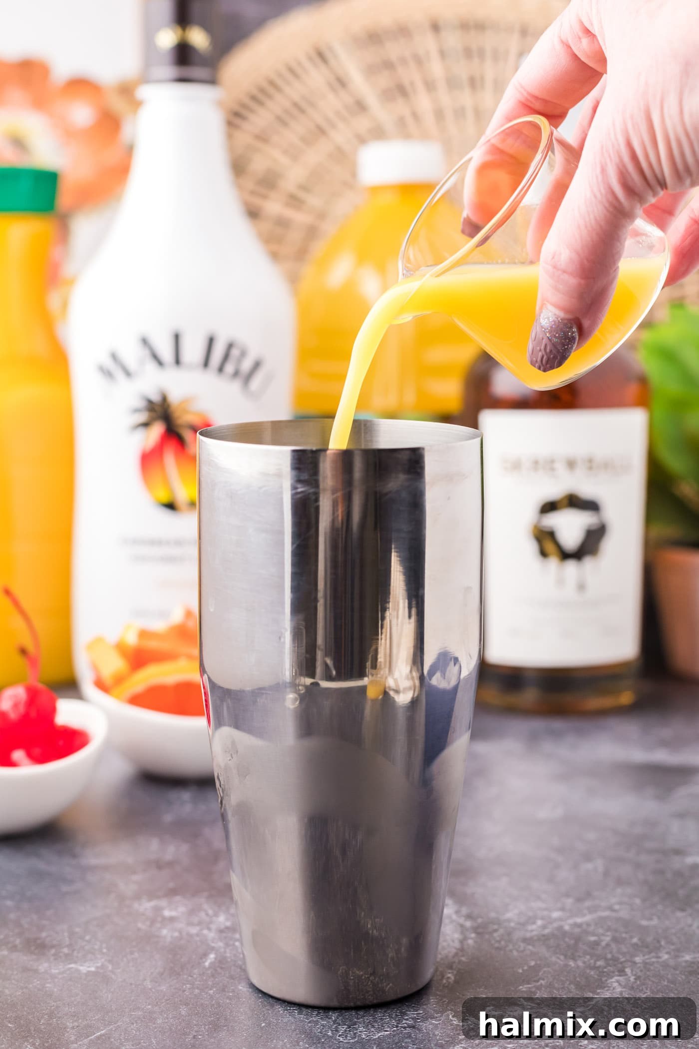 Pouring orange and pineapple juice into the cocktail shaker with rum and whiskey.