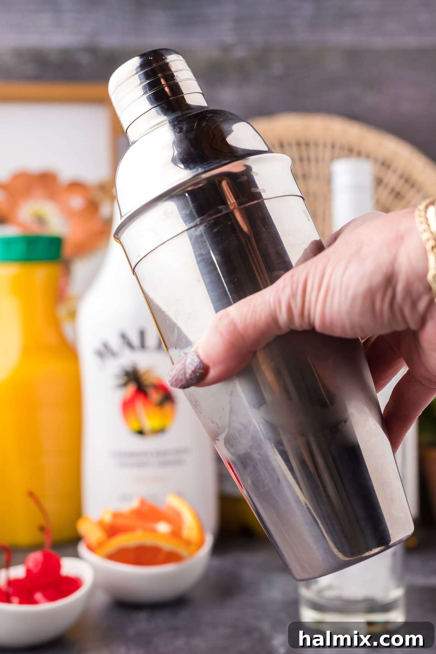 A person vigorously shaking a cocktail shaker to mix the drink.