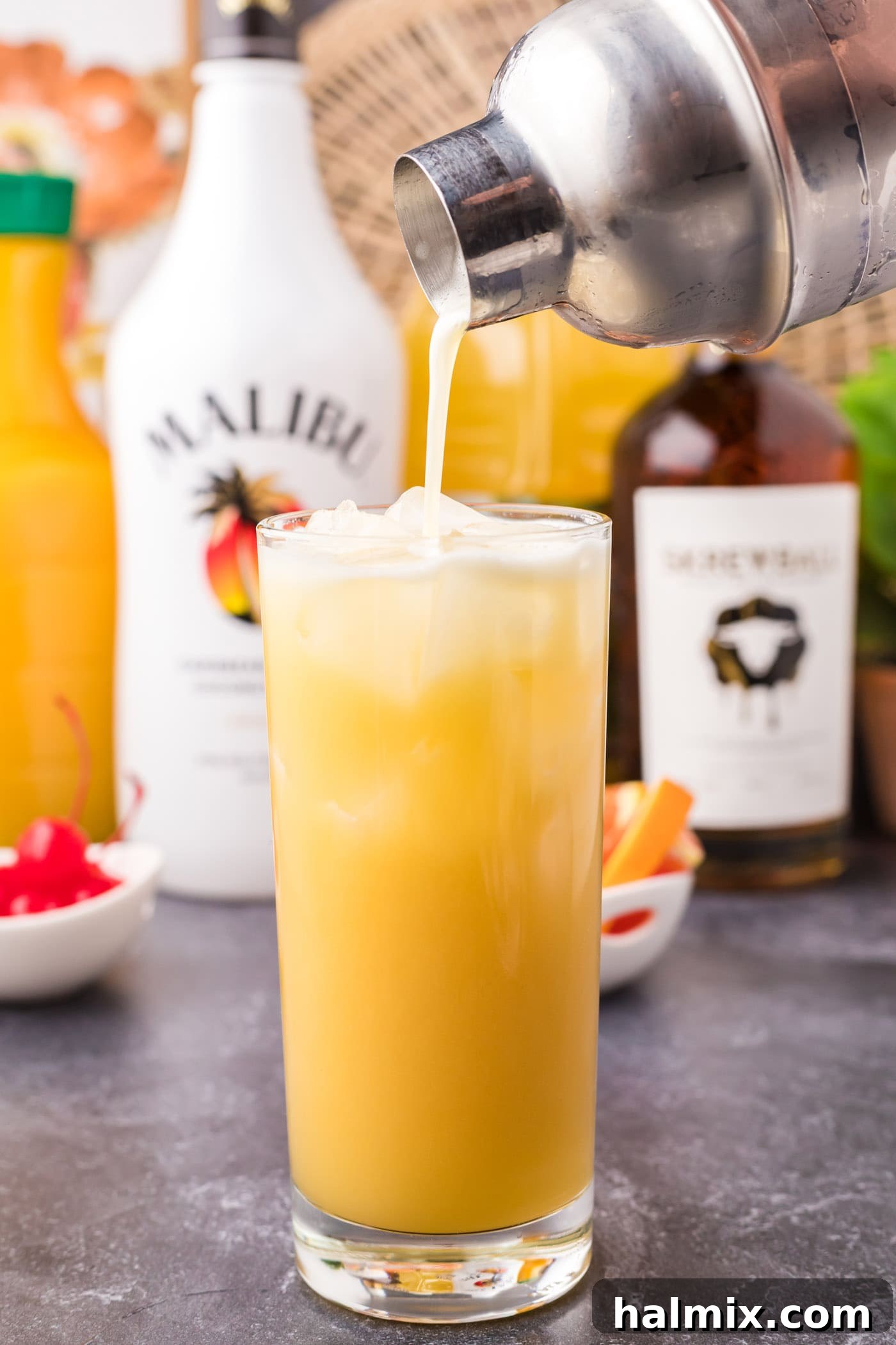 Pouring the Skrew Loose Cocktail from the shaker into a highball glass filled with ice.