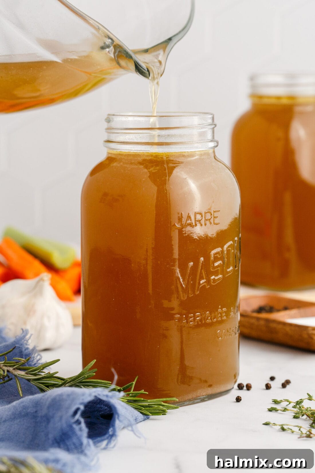 Homemade Chicken Stock being poured into a mason jar, showcasing its golden hue and richness.