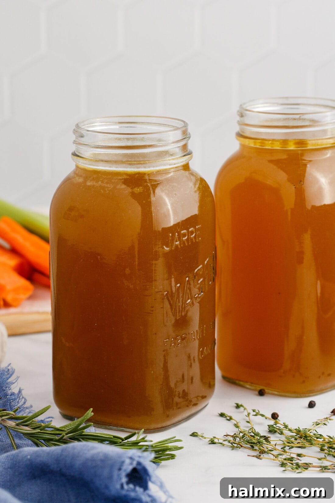 Two jars of freshly made Homemade Chicken Stock, ready for storage.