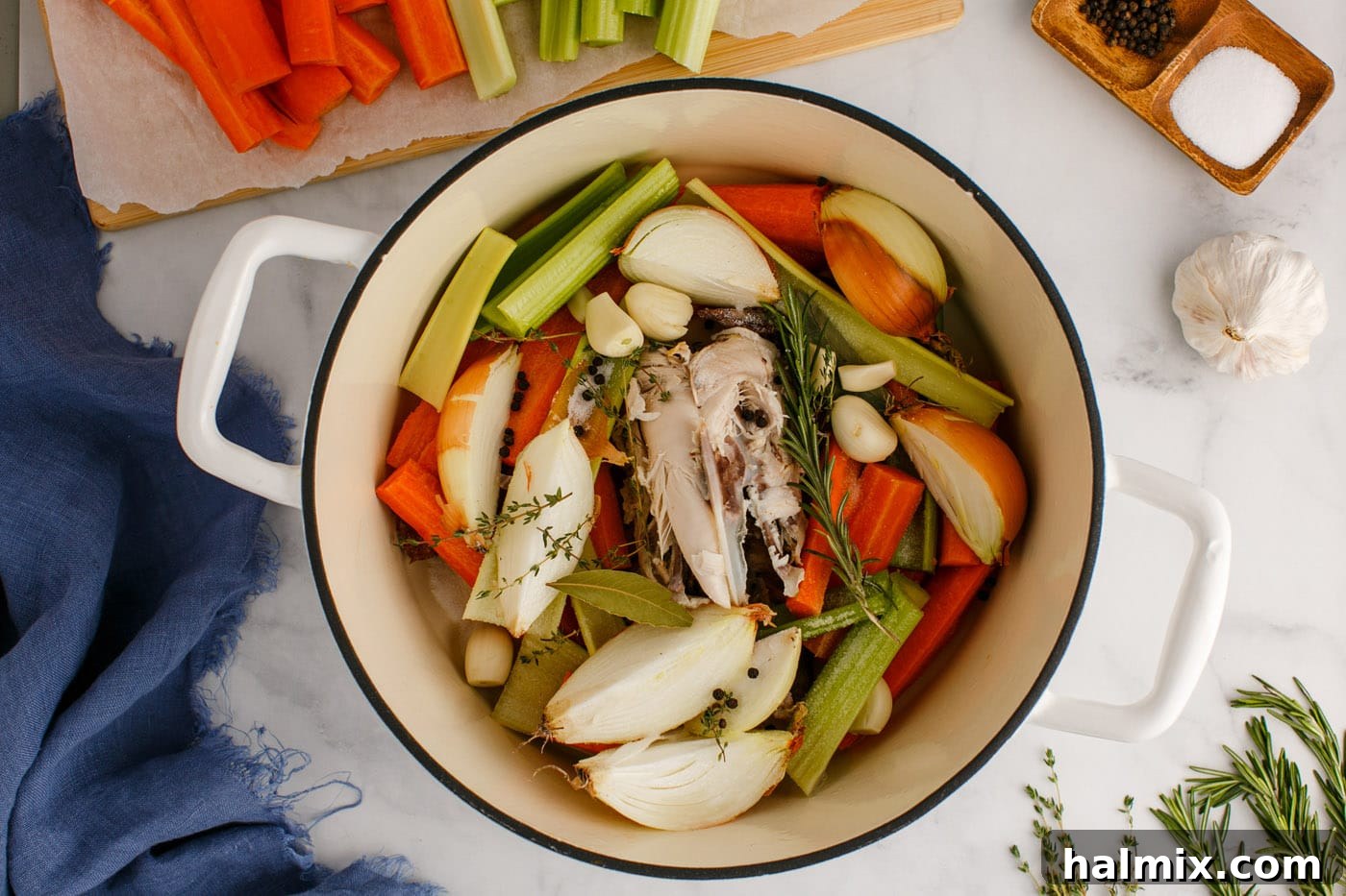 Adding fresh herbs to the pot of homemade chicken stock ingredients.