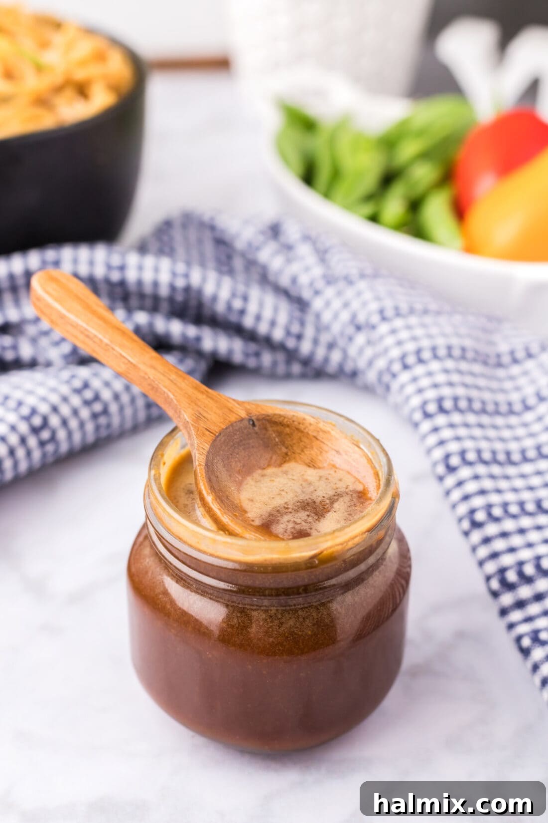 A wooden spoon resting invitingly in a jar of freshly made Homemade Teriyaki Sauce, highlighting its rich, glossy texture.
