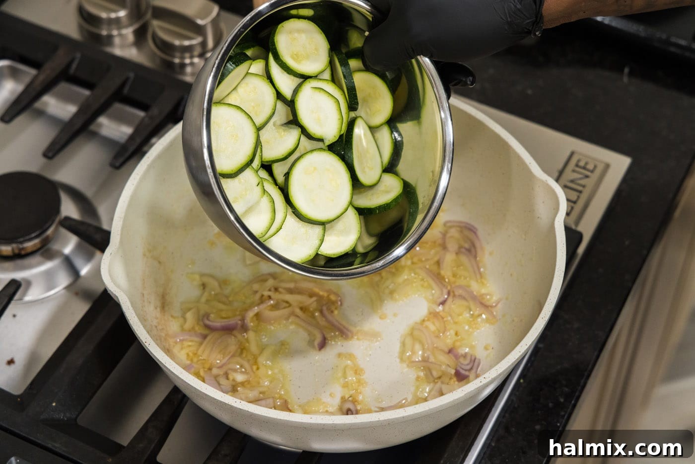 pouring sliced zucchini into a skillet with shallots, garlic, and butter