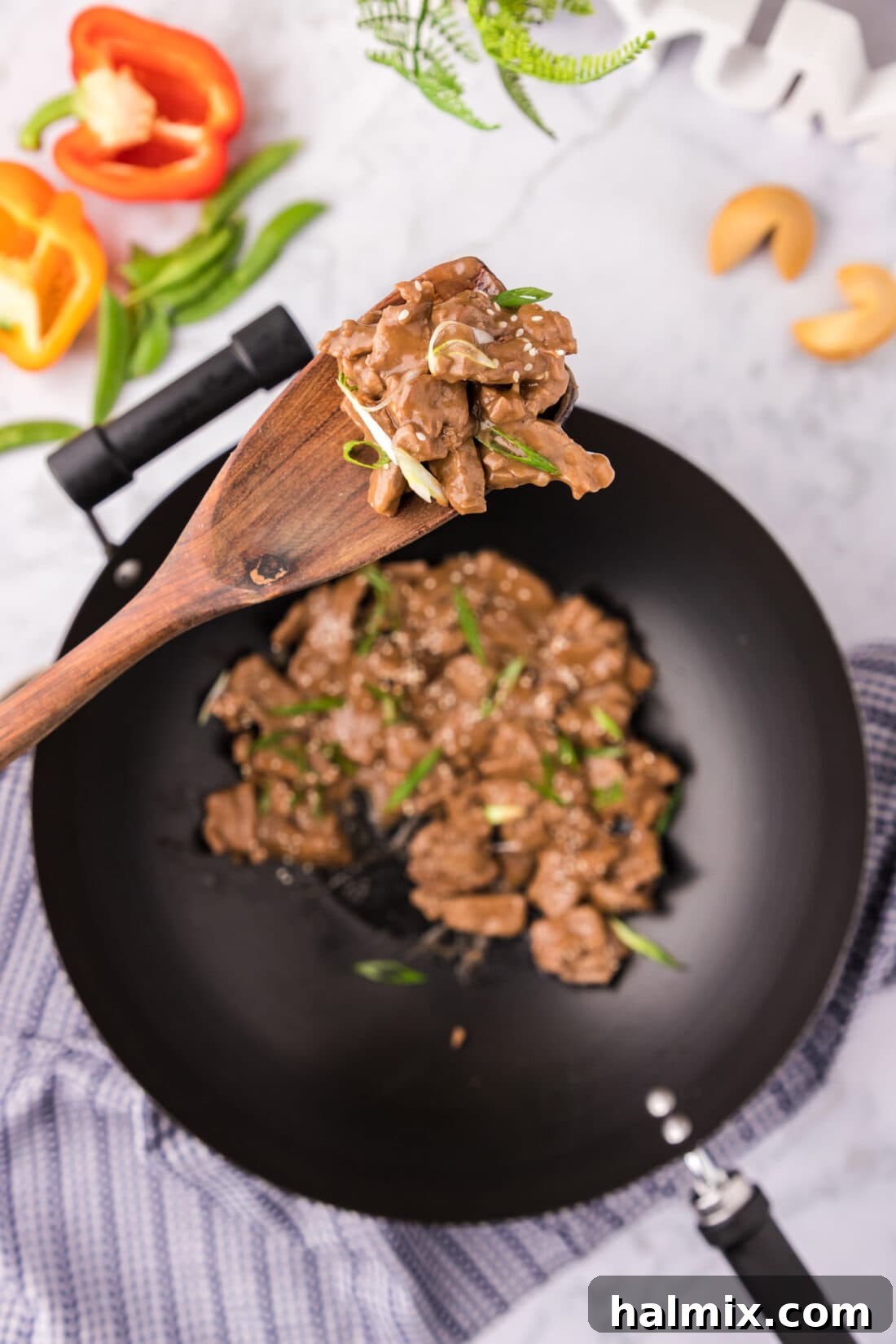 Spoonful of Beef Teriyaki held above a skillet of Beef Teriyaki