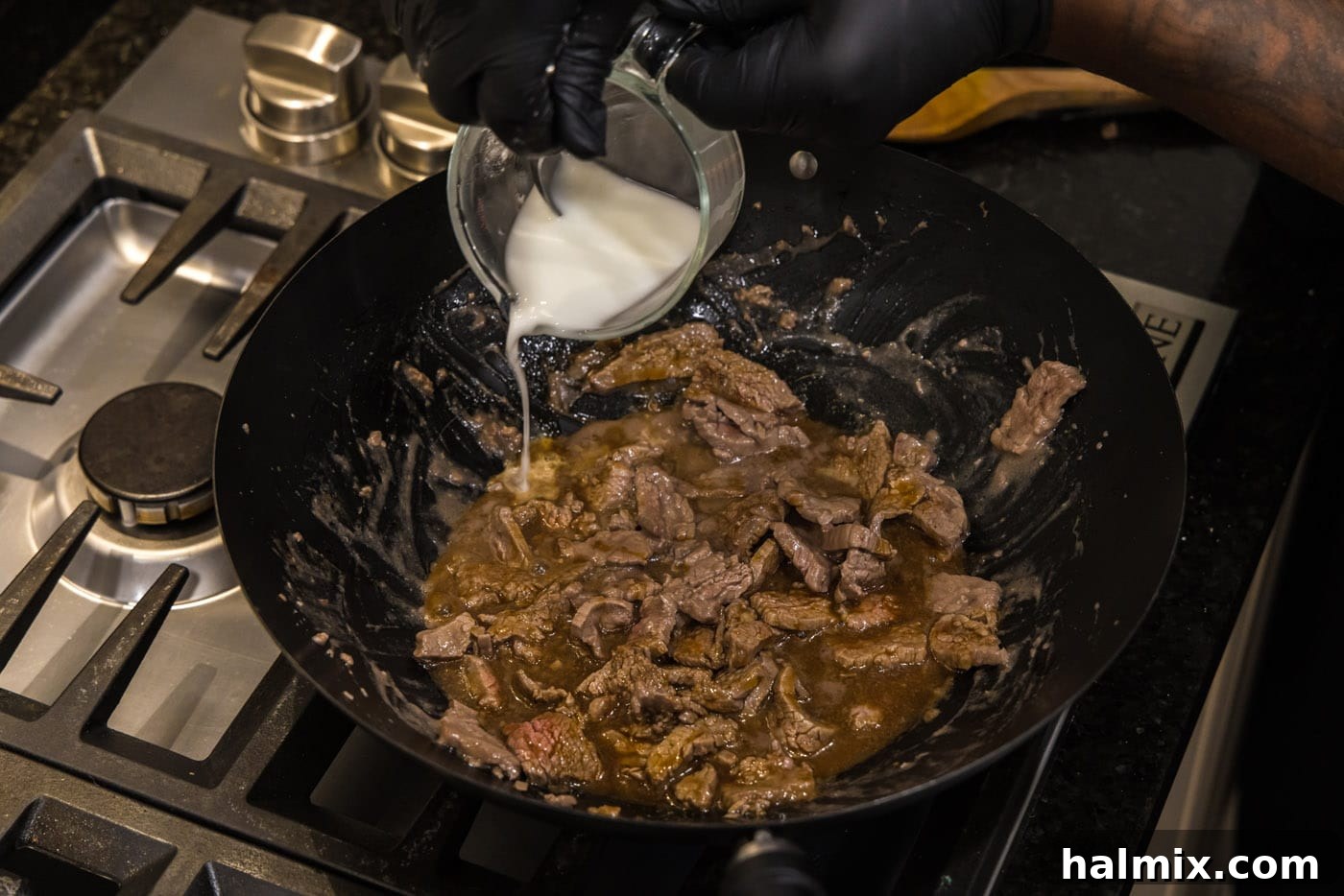 adding cornstarch water to skillet with beef strips and teriyaki sauce