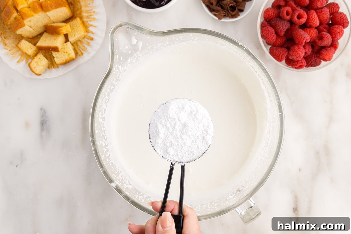 adding powdered sugar to heavy whipping cream in a bowl
