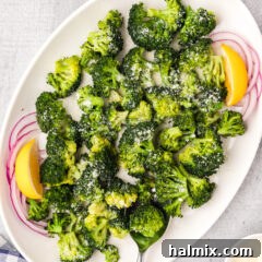 Instant Pot Broccoli on a white platter with onions and lemon wedges
