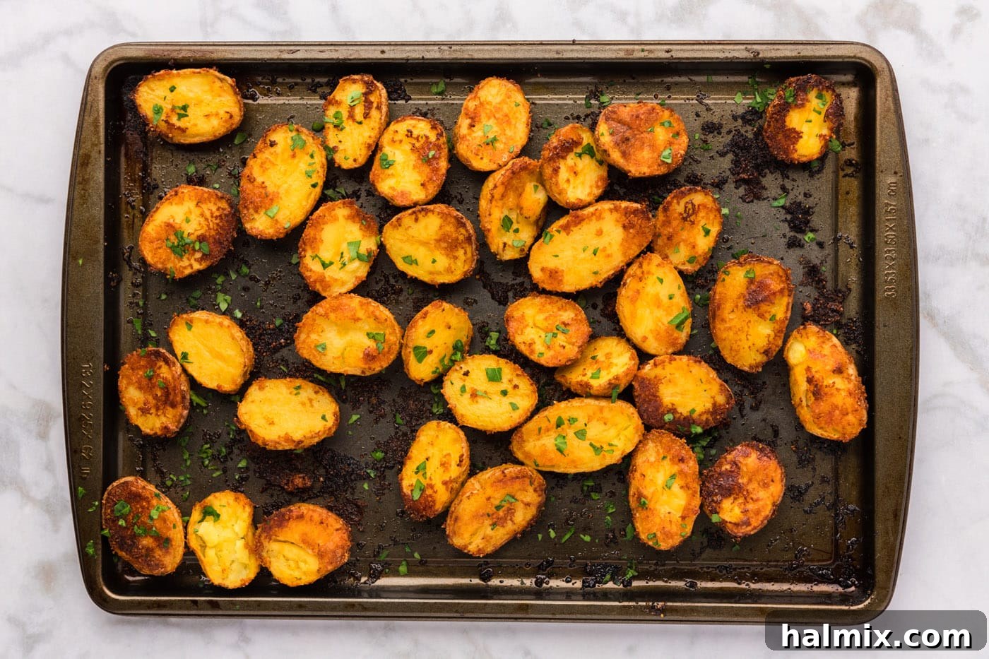 Perfectly roasted golden-brown parmesan potatoes on a baking sheet, just out of the oven