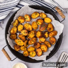 Parmesan Potatoes arranged in a metal serving tray, garnished with fresh herbs