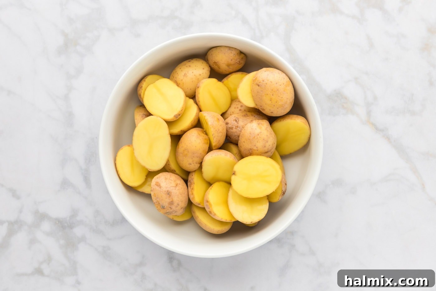 Sliced small Yukon Gold potatoes resting in a large mixing bowl