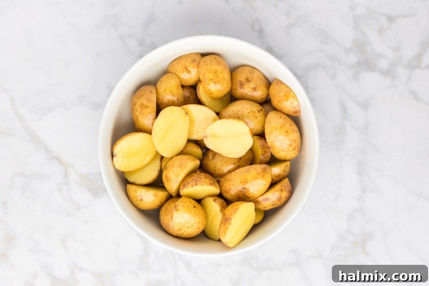 Sliced potatoes after being tossed thoroughly with olive oil, showing an even coating