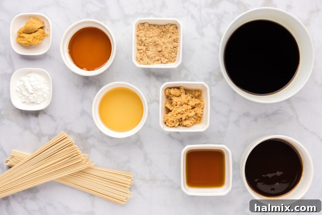 A collection of ingredients for Teriyaki Noodles laid out on a cutting board, including noodles, sauce ingredients, and garnishes