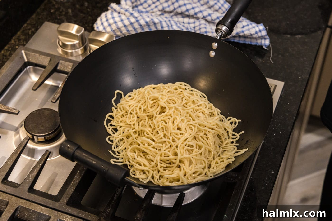 Cooked lo mein noodles resting in a large wok
