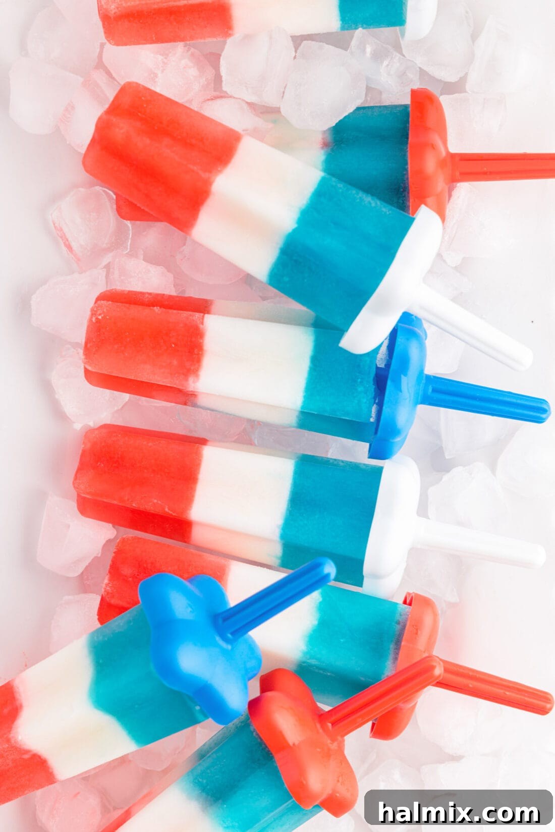 A tray of freshly made Patriotic Bomb Pops on ice, showcasing their distinct red, white, and blue layers.