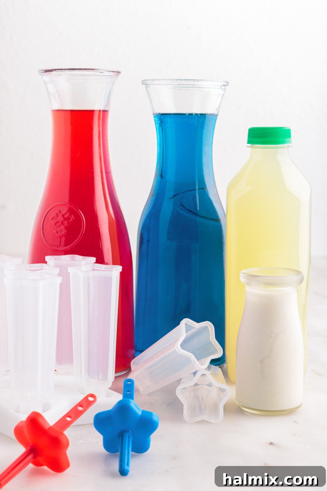 Arrangement of ingredients for Patriotic Bomb Pops, including Kool-Aid packets, limeade, and heavy cream.