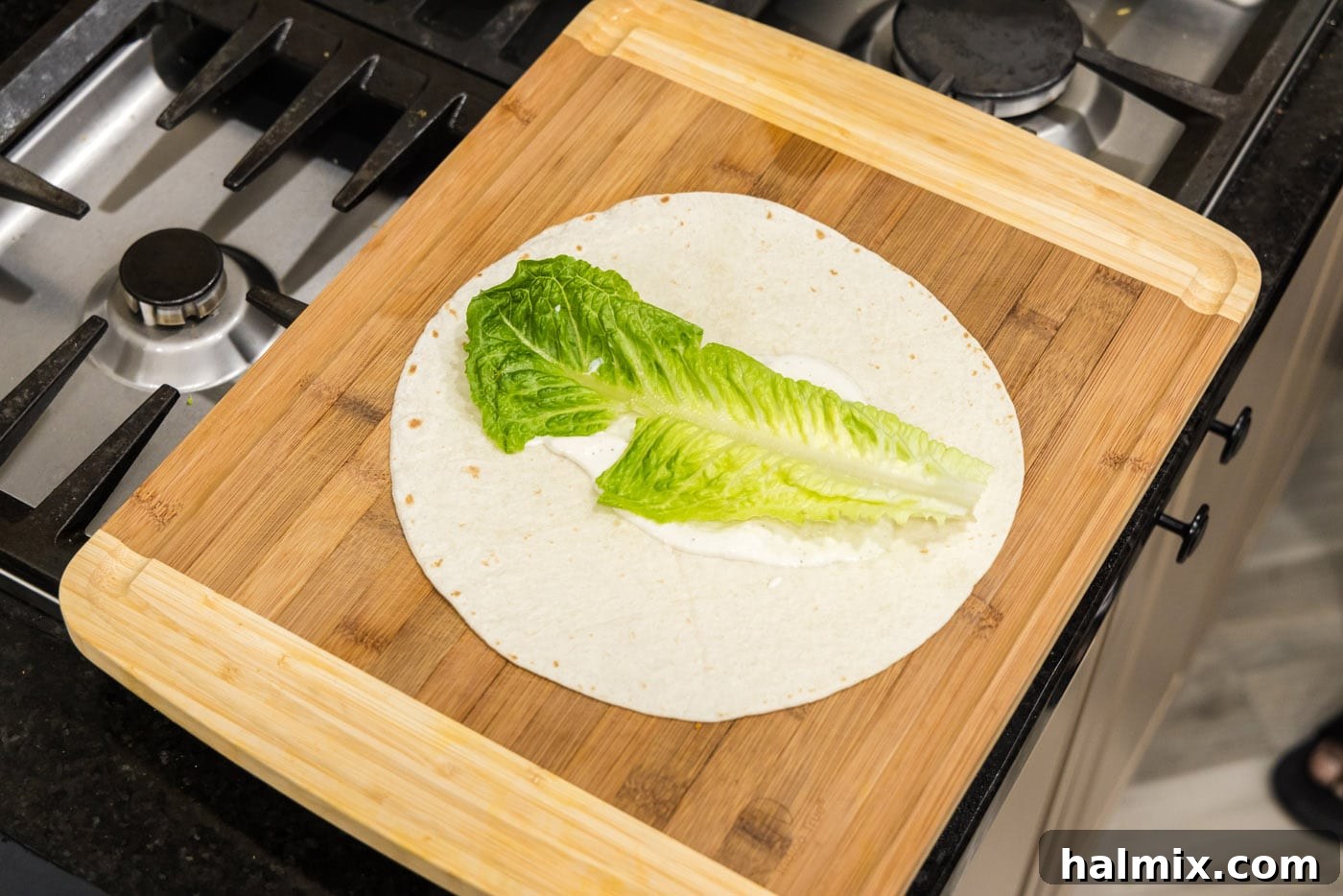 lettuce leaf on top of ranch dressing and tortilla