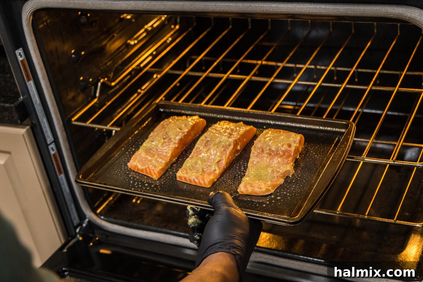 hand putting salmon filets into oven