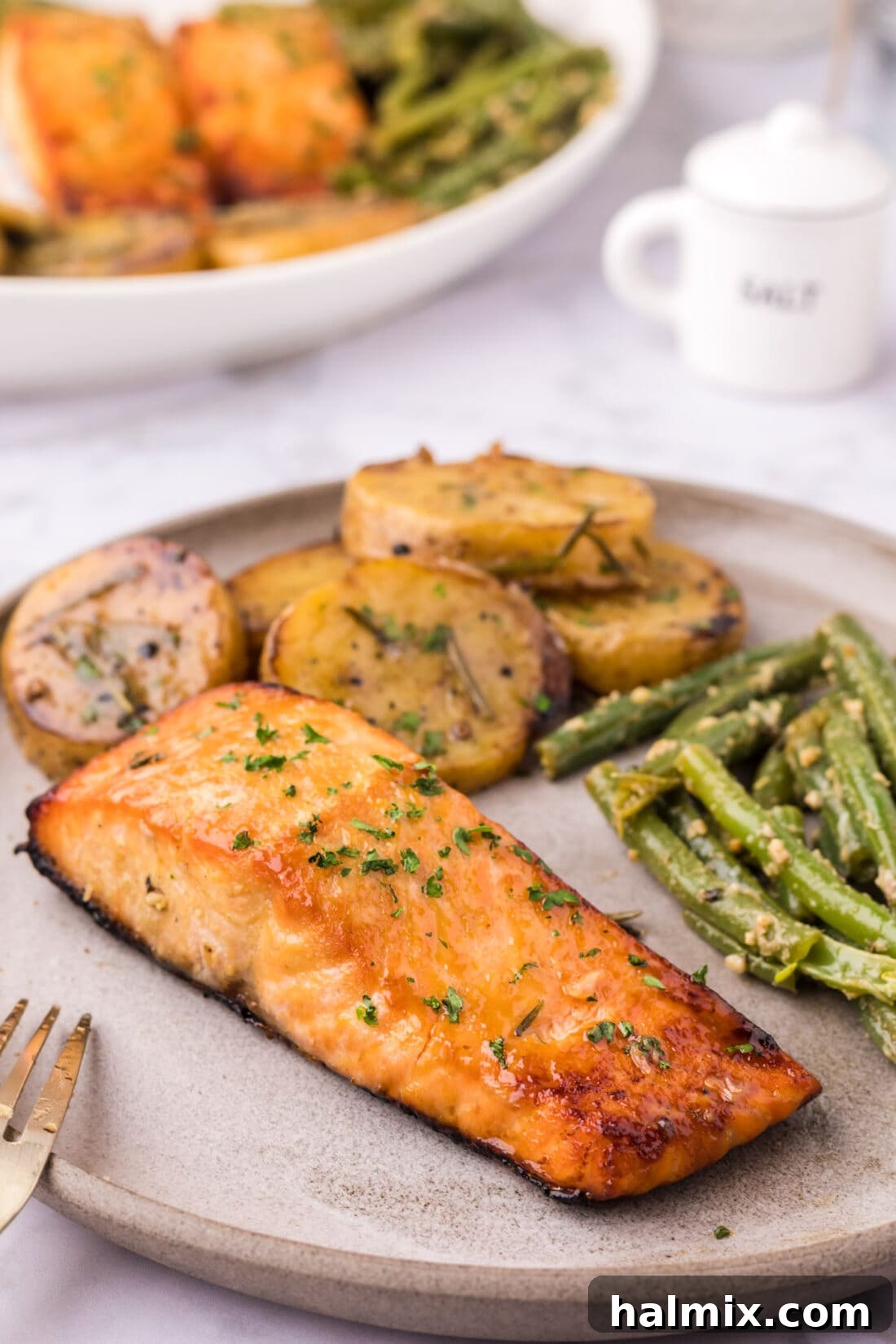 Brown Sugar Salmon on a plate with melting potatoes and garlic green beans