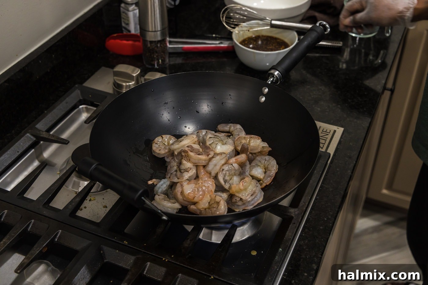 Stir-frying shrimp in a wok until they are perfectly pink and tender.