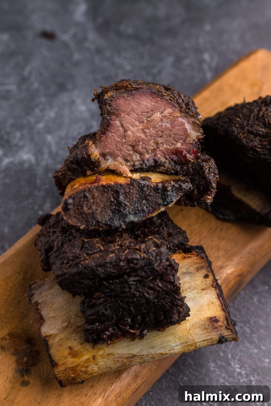 Two succulent smoked beef short ribs stacked on a cutting board, ready to be served.