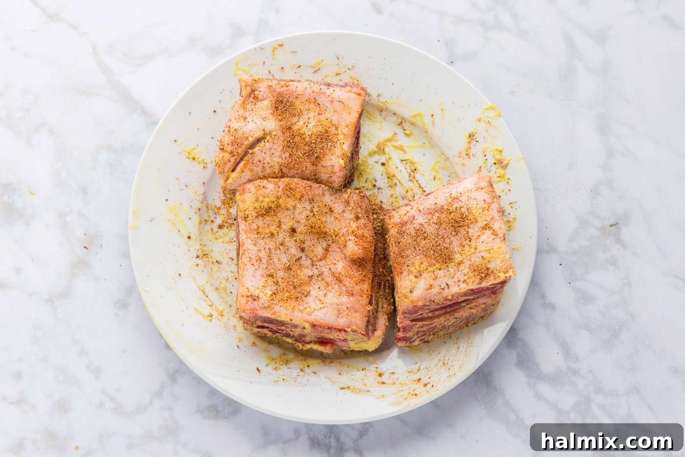 Seasoned beef short ribs with Dijon mustard visible, ready for the smoker.