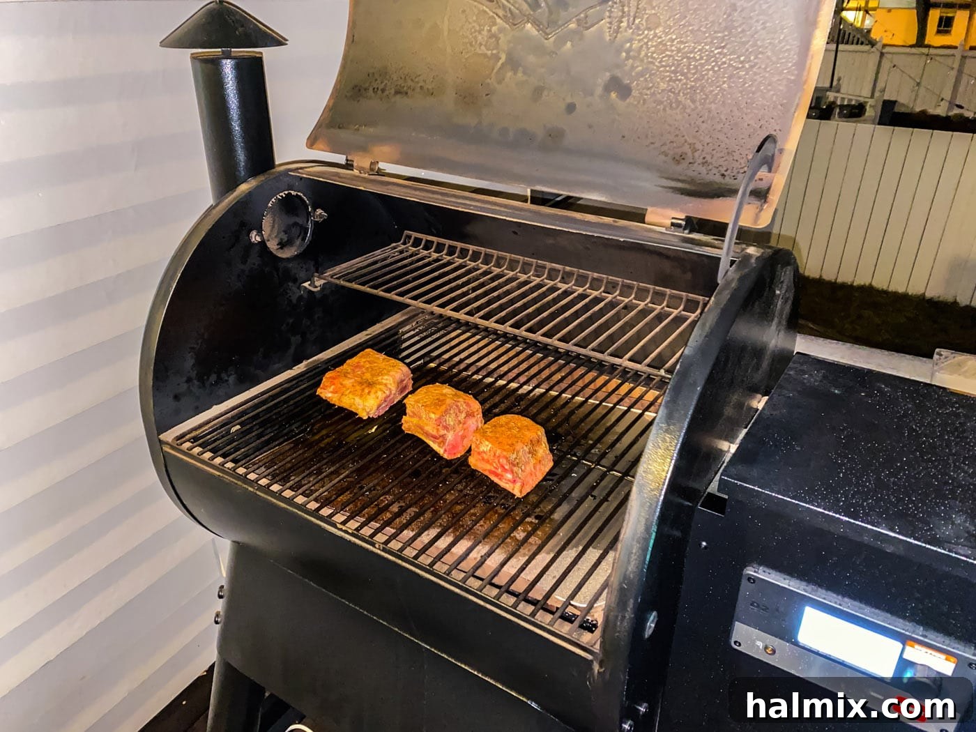 Beef short ribs arranged on the grates of a preheated smoker, beginning their slow cook.