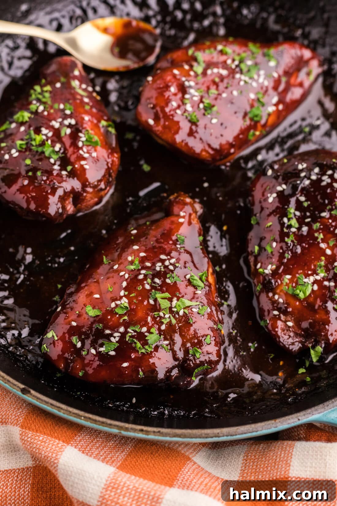 Close up photo of Honey Garlic Chicken Breasts in a skillet, glistening with sauce.
