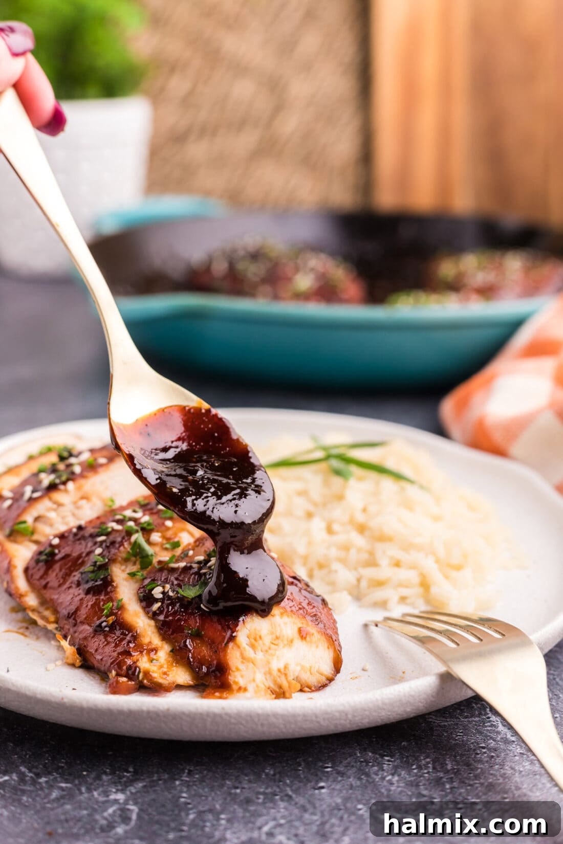 Spoonful of sticky honey garlic sauce being drizzled over a cooked chicken breast.