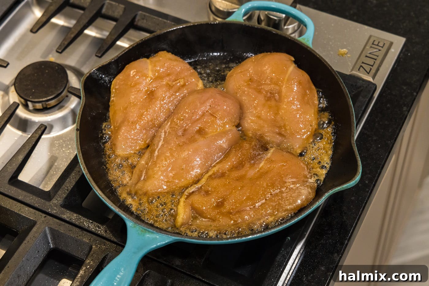 Chicken breasts searing in a hot skillet with olive oil.