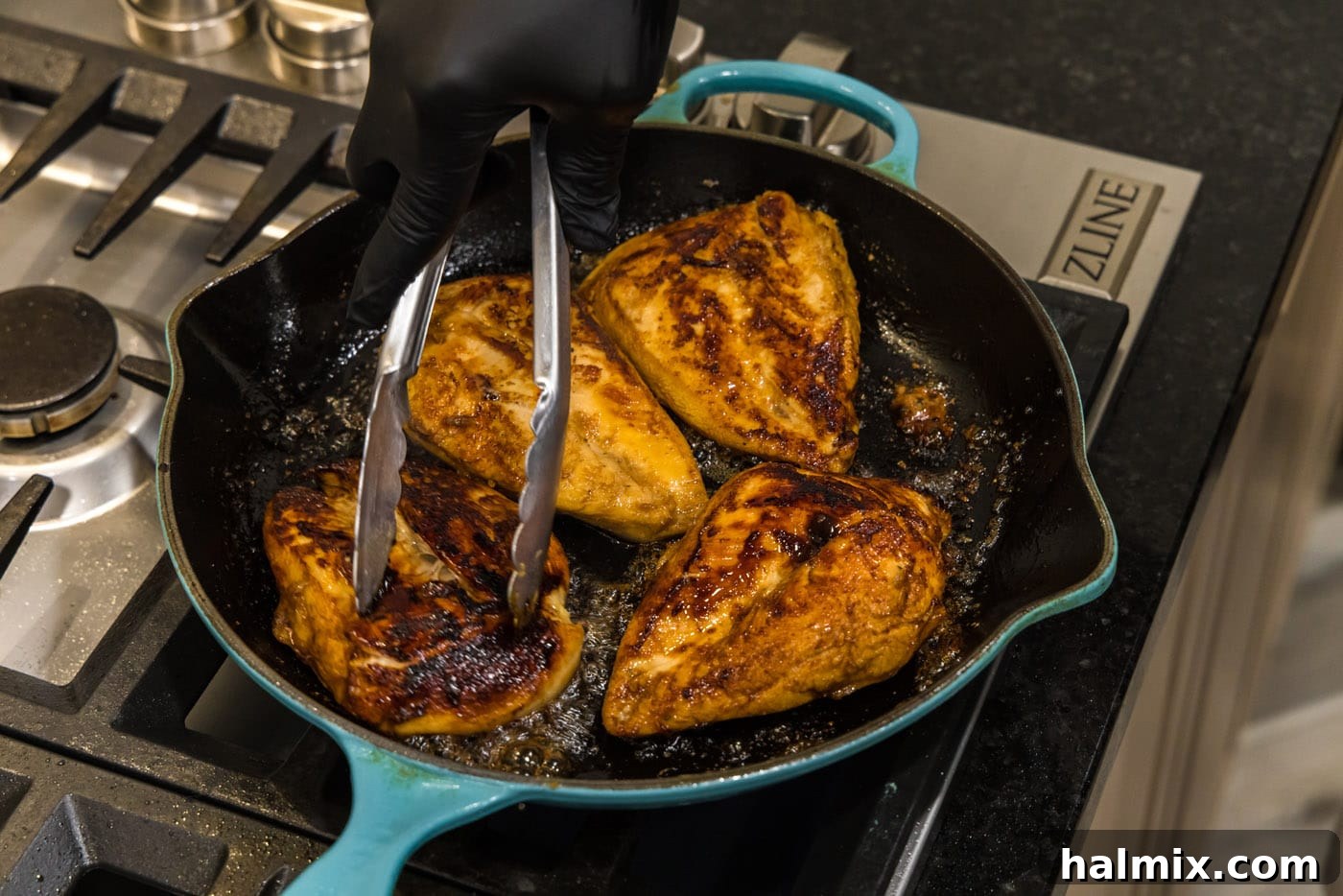 Flipping chicken breasts to sear the second side in a skillet.