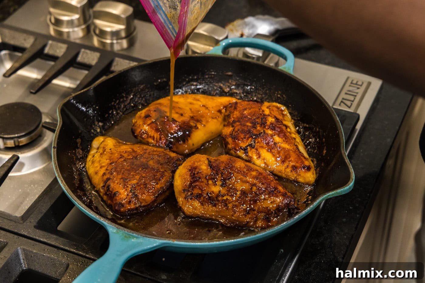 Pouring the reserved marinade over searing chicken breasts in a skillet.