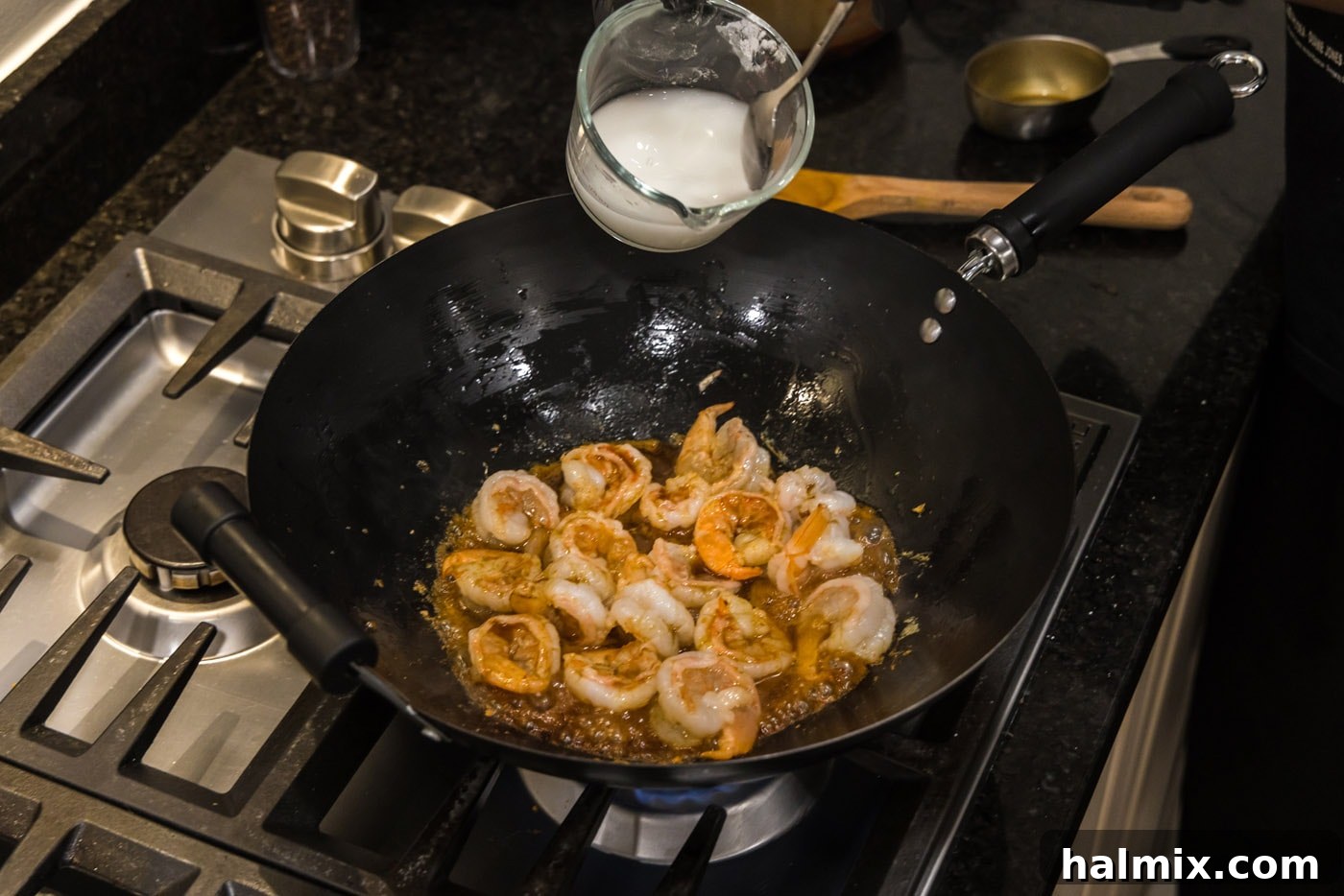 Sticky Teriyaki Shrimp 9 A cornstarch slurry being poured into the teriyaki shrimp in the wok to thicken the sauce.