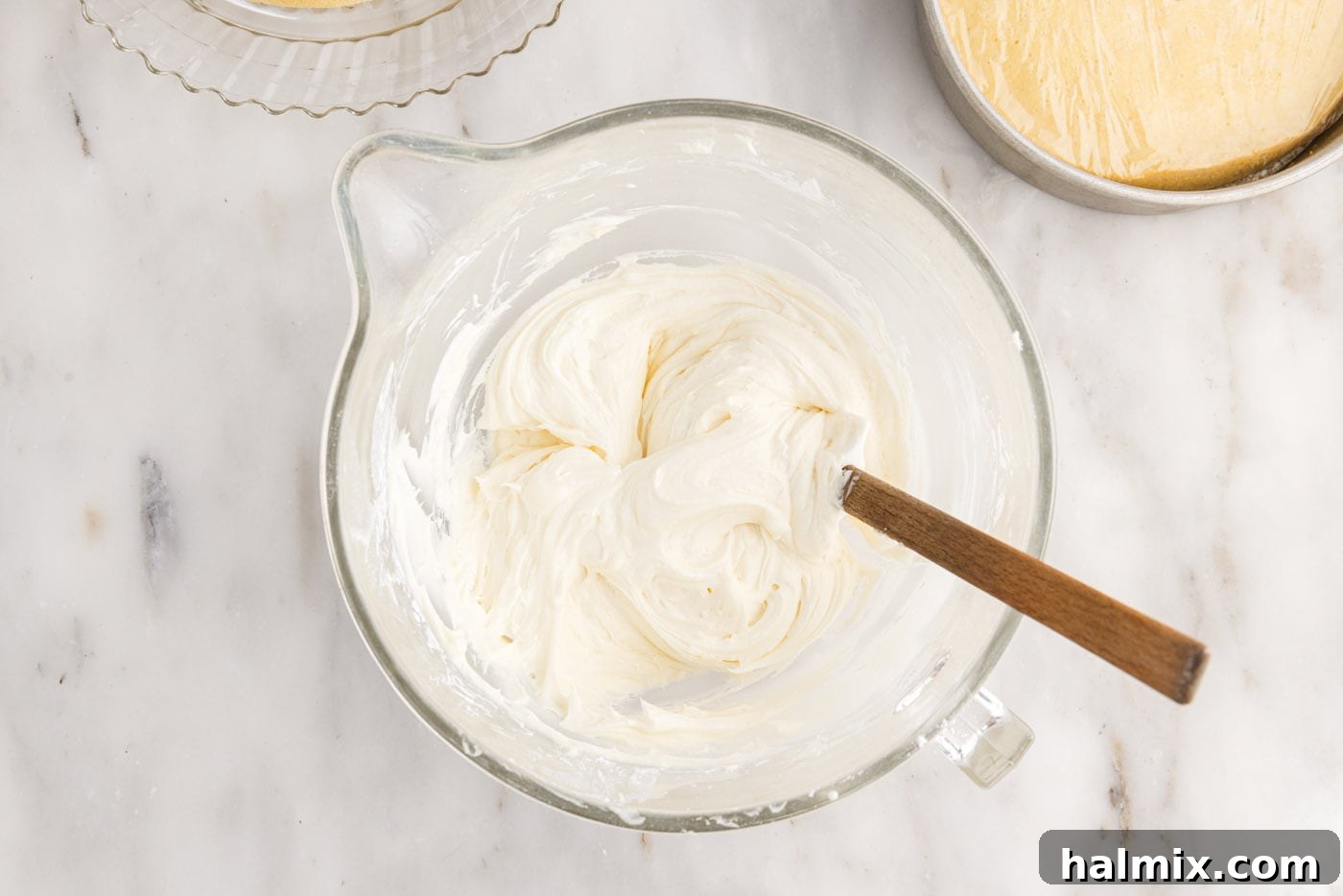 Creamy, fluffy cream cheese frosting prepared in a mixing bowl, showcasing its smooth and spreadable consistency.