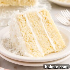 A beautifully sliced piece of coconut cake on a plate, showcasing its moist layers and creamy frosting.